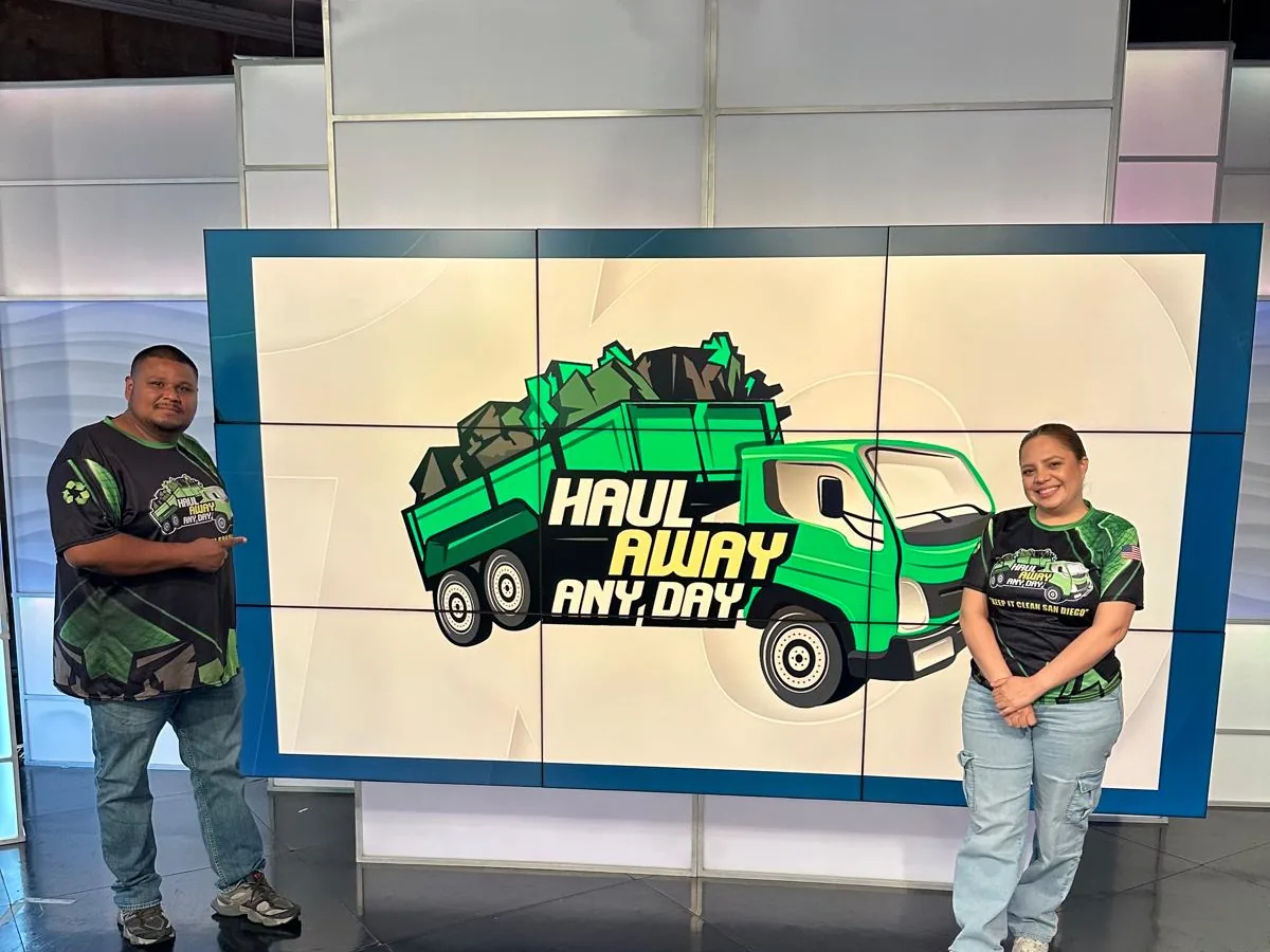 The Haul Away Any Day team next to the company logo on a studio video wall