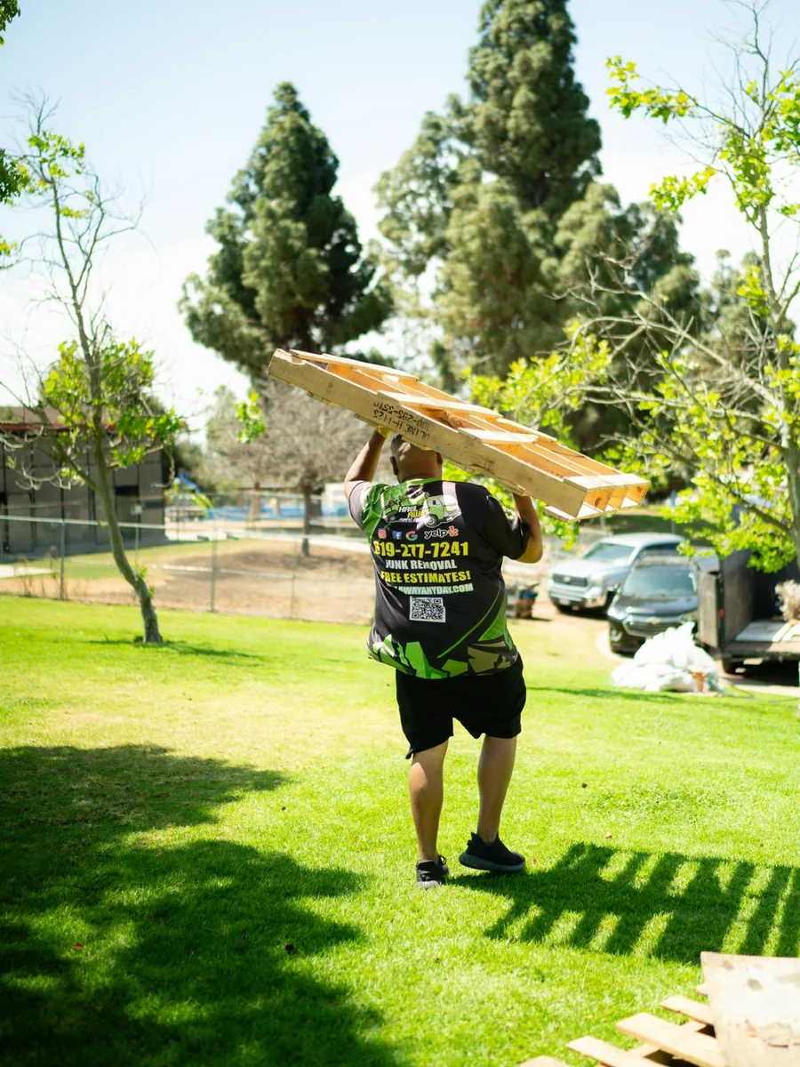 Haul Away Any Day crew member carrying wooden pallets to the trailer